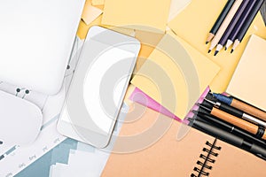 Desktop with empty white smartphone and supplies