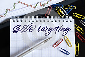 On the desktop are a forex chart, paper clips, a pen and a notebook in which it is written - GEO targeting