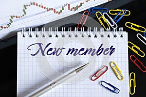 On the desktop are a forex chart  paper clips  a pen and a notebook in which it is written - New member