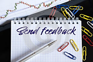 On the desktop are a forex chart, paper clips, a pen and a notebook in which it is written - Send feedback