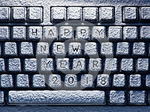 Desktop keyboard covered with white snow with title happy new year 2018