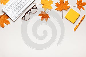 Desktop keyboard glasses note paper with autumn maple leaves. Top view flat lay copy space
