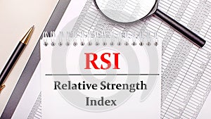 Desktop magnifier, reports, pen and notebook with text RSI Relative Strength Index. Business concept