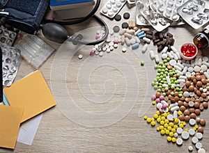 Desktop of a medical worker. Scattered pills of various shapes in color, a medical tonometer and paper with a pencil