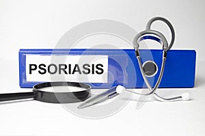 On the desktop is a stethoscope, documents, a pen, and a red file folder with the text PSORIASIS. Medical concept