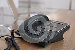 Desktop telephone on wooden table in office. Hotline service