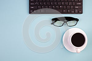 Desktop. Top view with copy space. Keyboard, glasses, cup of coffee on a light background