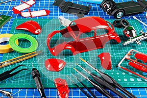 Desktop view assembly and painting of a red retro scale model car vehicle concept background. modeling tools airbrush gun paint