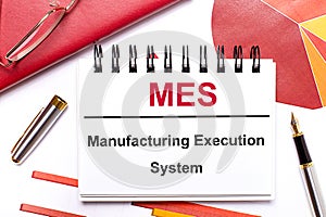 On the desktop is a white notebook with the text MES Manufacturing Execution System