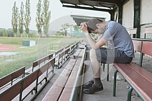 Despair and depressed man is sitting in stadium. Solitary and loneliness concept