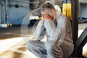 Despair healthcare worker in white covid protective overalls. Tired Male caucasian doctor grabs his head cower in depression