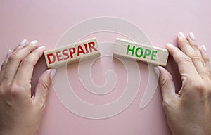 Despair or Hope symbol. Concept word Despair or Hope on wooden blocks. Businessman hand. Beautiful pink background. Business and