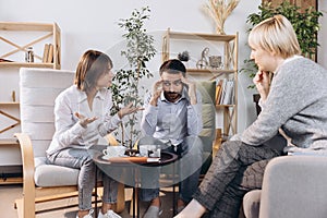 Unhappy married couple, sad, depressed man and woman meeting with doctor, psychologist to solve family problem.