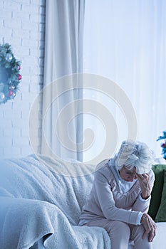 Despair senior woman on sofa
