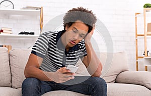 Despair teen guy reading bad news on smartphone at home