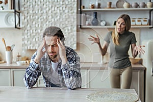 Despaired offended millennial european man with stubble hold his head with hands, ignoring screaming lady after scandal