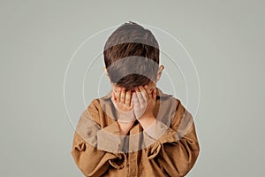 Despaired sad little child 6 years old in casual crying isolated on gray background, studio, close up