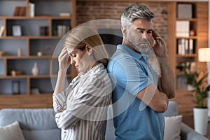 Despaired sad middle aged european male ignores offended woman in living room interior, back to back