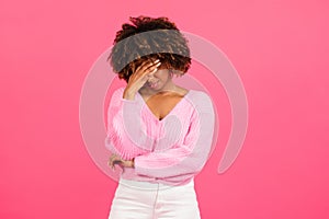 Despaired sad millennial african american curly woman in casual covering her face with hand, crying