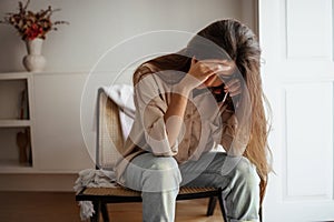 Despaired sad millennial mixed race female calls by phone, talks, sits on chair, suffering from bad news