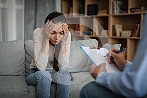 Despaired sad young caucasian lady suffering from mental problems listens to male doctor in office