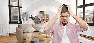 Despaired young man in messy room having headache