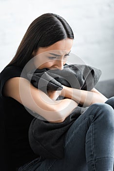 despaired young woman hugging pillow while suffering from depression at home.