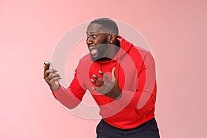 Desparate angry pissed african-american irritated man yelling smartphone look angry phone display gesturing dismay anger