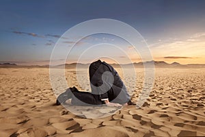 Desparate businessman hiding head in the sand