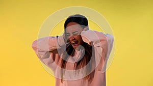Desperate african woman screaming and covering ears on yellow background