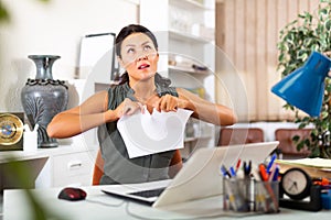 Desperate aggressive business woman ripping paper documents in office