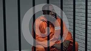 Desperate black prisoner sitting in cell, wrongly accused person, faulty system