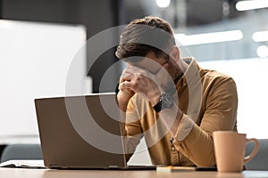 Desperate Businessman Near Laptop Covering Face Having Problem In Office