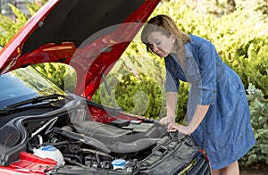 Desperate and confused woman stranded on roadside with broken car engine failure or crash accident