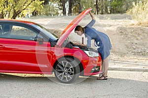 Desperate and confused woman stranded on roadside with broken car engine failure or crash accident