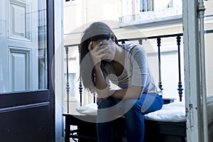 Desperate Latin woman sitting at home balcony looking destroyed and depressed suffering depression