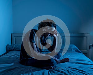 Desperate lonely teenager man suffering from depression sitting alone on bed