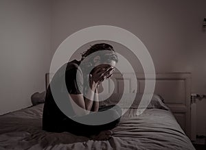 Desperate lonely teenager man suffering from depression sitting alone on bed