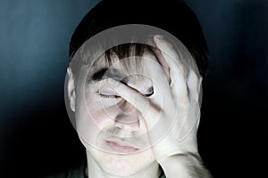 Desperate man holding head feeling headache portrait in dark environment, serious face thinking young men in black background