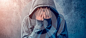 Desperate man in hooded jacket is crying photo