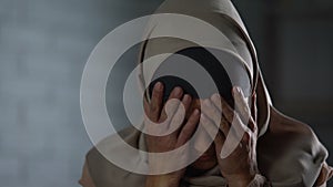 Desperate muslim woman crying, covering face with hands, family problem, shame