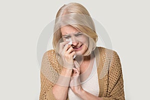 Desperate old woman crying wiping tears with handkerchief