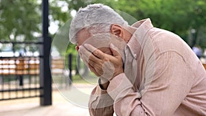 Desperate pensioner crying, covering eyes by hands, suffering loss, problem