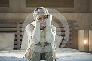 Dramatic lifestyle home portrait of attractive sad and depressed middle aged woman with grey hair on bed feeling upset suffering