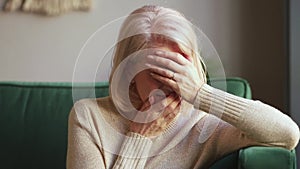 Desperate sad grieving old widow crying covering face with hands