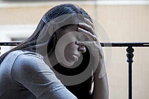 Desperate sad Latin woman at home balcony looking devastated and depressed suffering depression