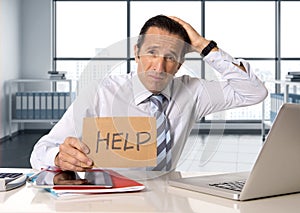 Desperate senior businessman in crisis working on computer laptop at office desk in stress under pressure