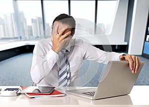 Desperate senior businessman in crisis working on computer laptop at office desk in stress under pressure