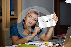 Desperate and stressed attractive middle aged Asian woman holding notepad asking for help feeling overworked and exploited working