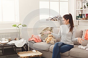 Desperate woman sitting on sofa in messy room